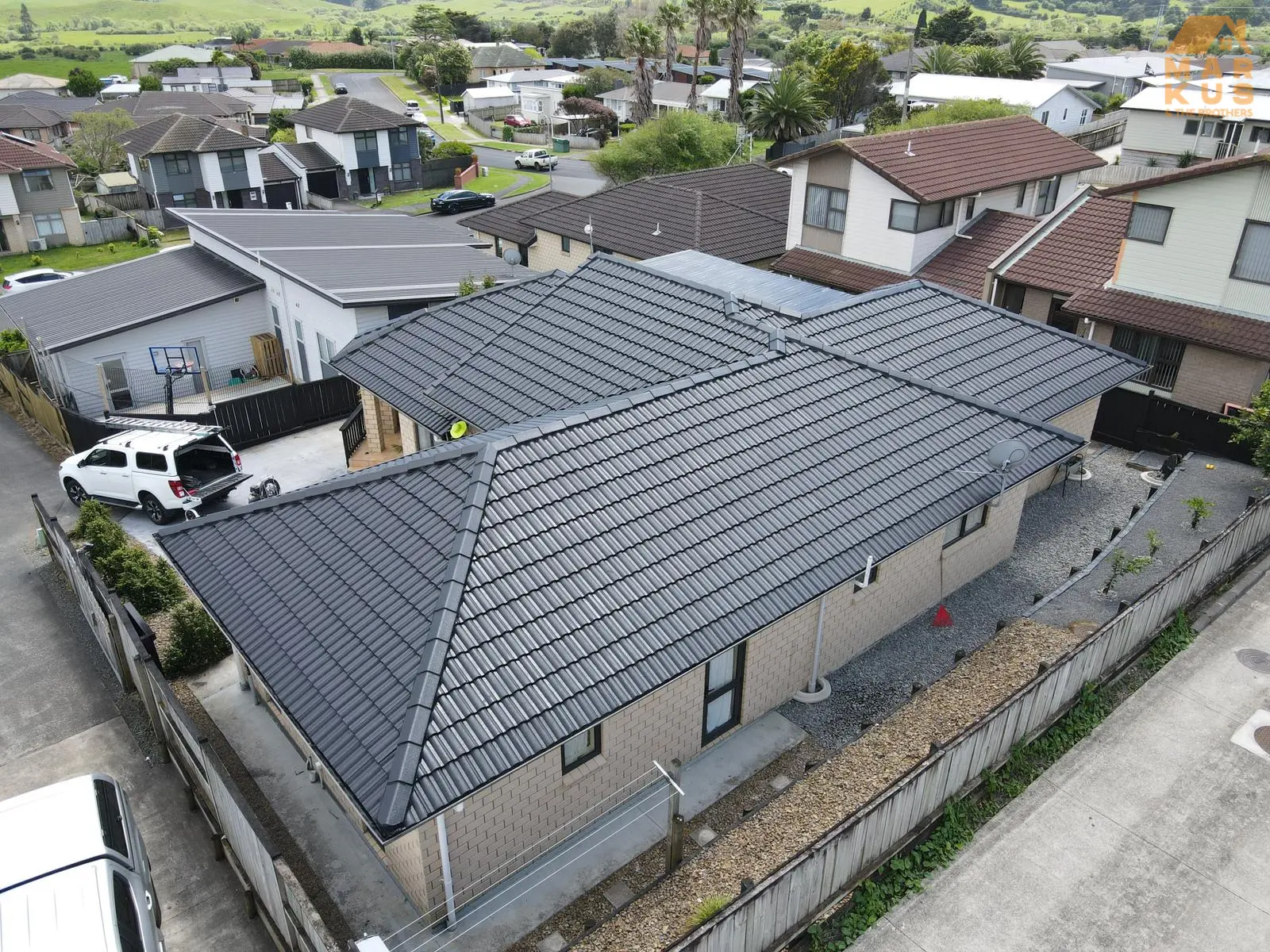Aerial view of house with new black tiled roof in suburban area.